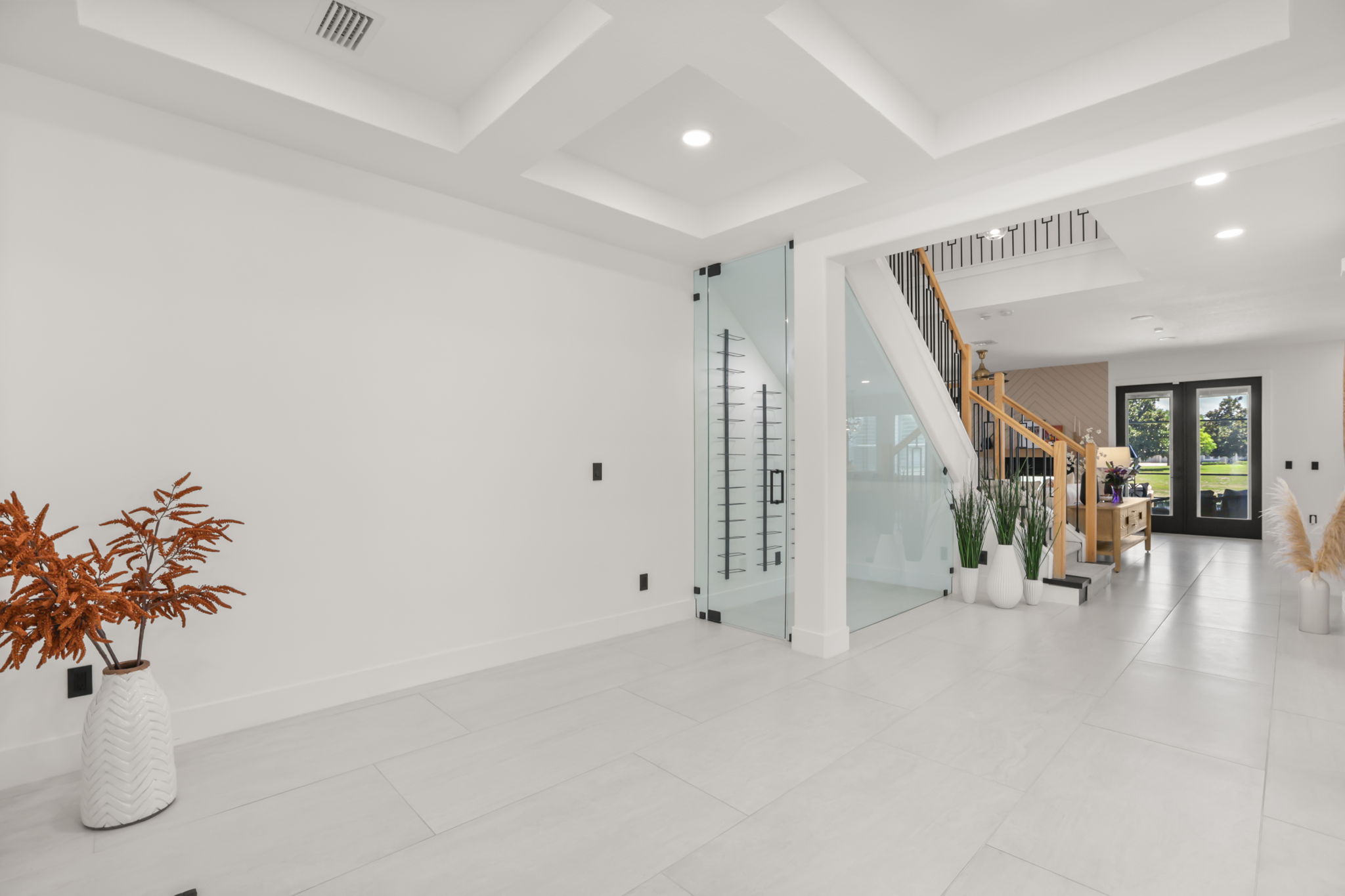 Two-story foyer with designer staircase and angled-glass wine room beneath the stairs